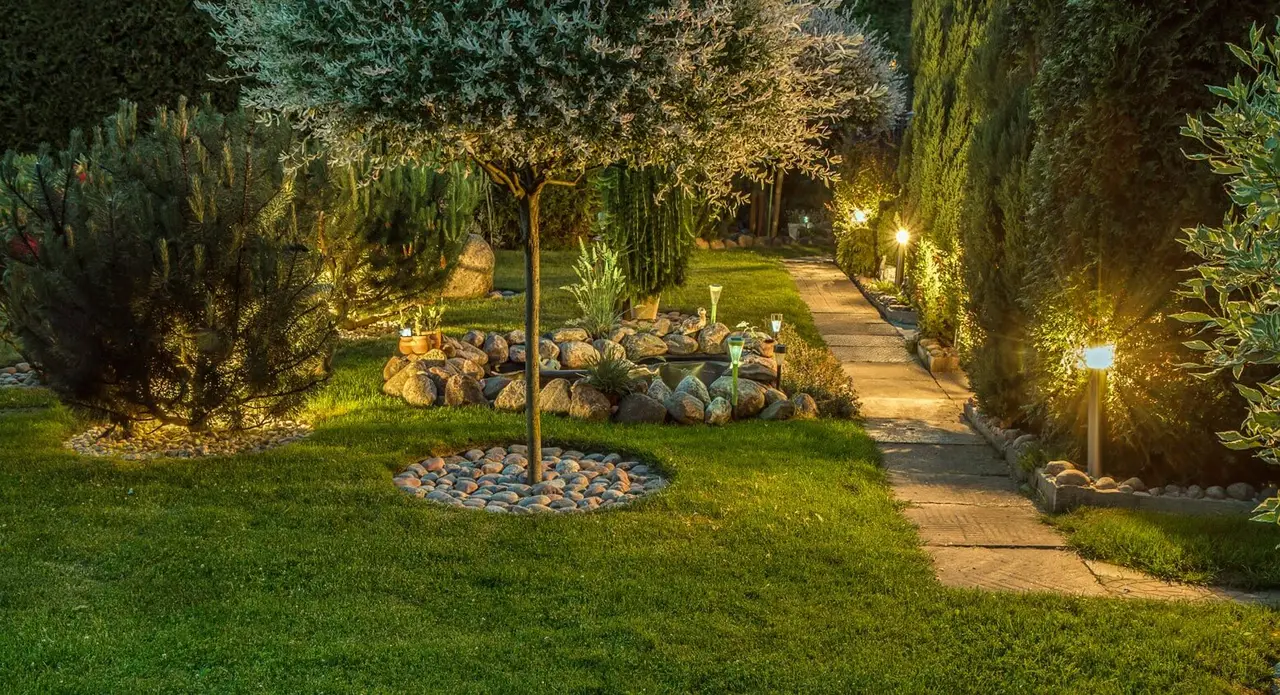 Stimmungsvoll beleuchteter Garten mit Natursteinweg und dichter Bepflanzung